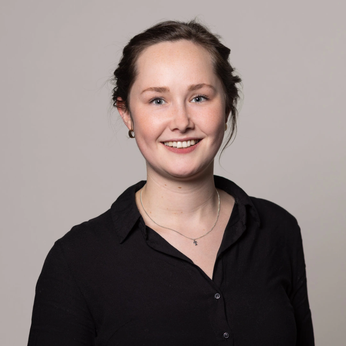 Portrait von Tina Wilming – herzlich lächelnd mit hochgesteckten dunklen Haaren und schwarzem Hemd
