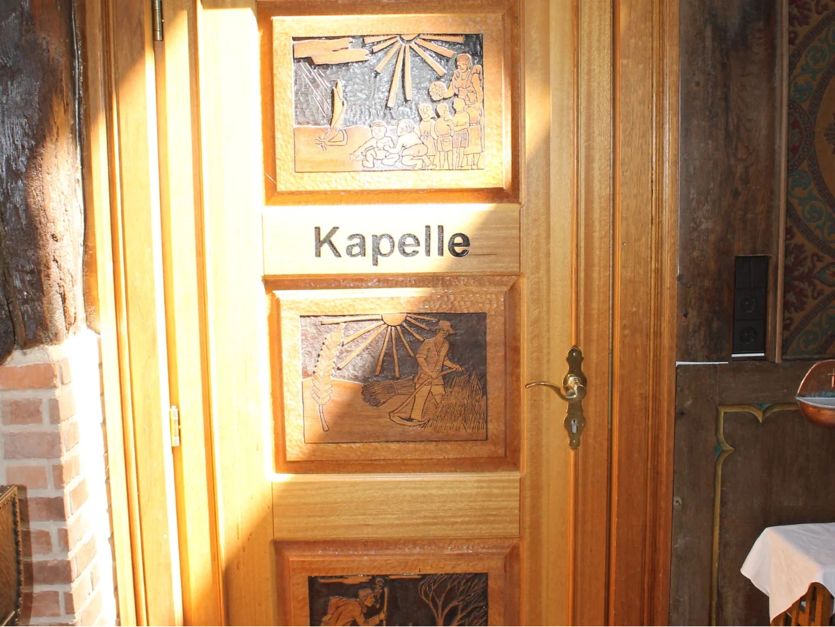 Holztür mit der Aufschrift 'Kapelle', verziert mit geschnitzten Bildern, die in die Kapelle des St. Josef Stifts führt.